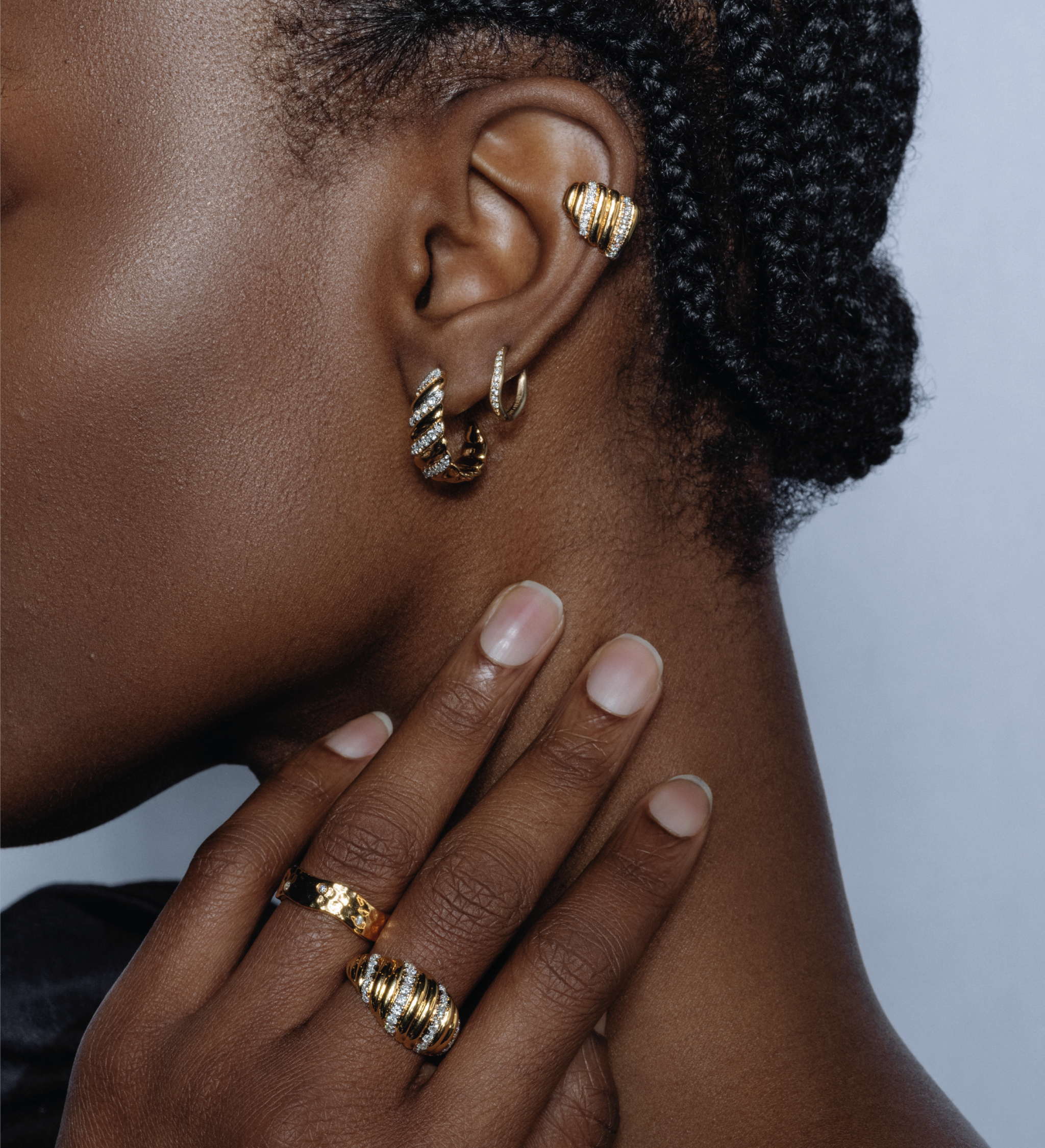 Close-up of a model wearing the gold Palm Diamond Ear Cuff, styled with matching gold diamond rings and hoop earrings.
